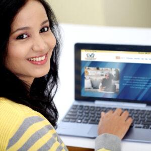 Smiling woman uses a laptop to prepare for her LMSW using Social Work Exam Strategies, LLC online tools