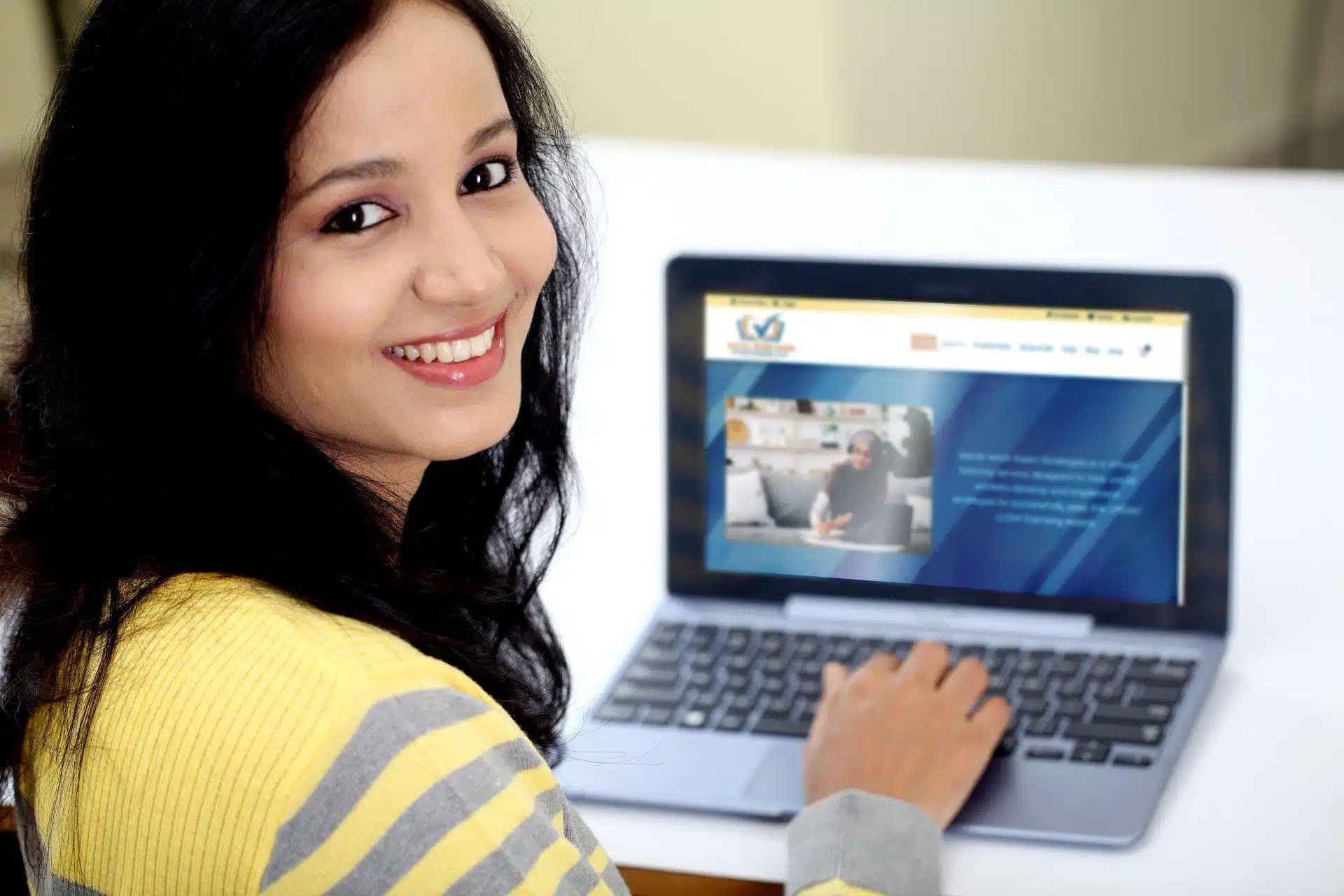 Smiling woman uses a laptop to prepare for her LMSW using Social Work Exam Strategies, LLC online tools